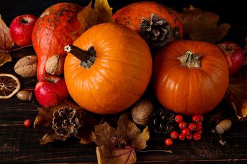 Orange pumpkins, fallen leaves, apples, nuts, berries on wooden background. Concept autumn template, blank halloween or Thanksgiving day. Copy space.