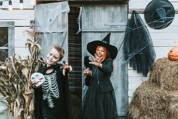 children a boy in a skeleton costume and a girl in a witch costume having fun at a Halloween party on the decorated porch
