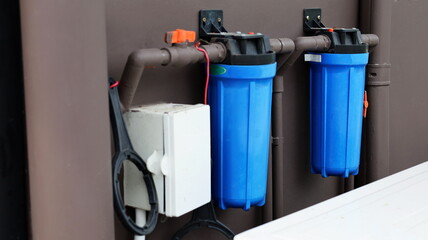 Housing water filter. A blue water filter mounted on the wall for purifying water. Close focus and select objects.