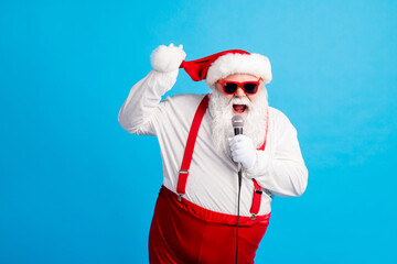 Fototapeta na wymiar Photo of hipster funky pop star celebrity santa claus with beard big abdomen sing song microphone wear style stylish suspenders overalls headwear sunglass isolated blue color background