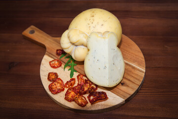 Cheese on a wooden plank with herbs and tomato