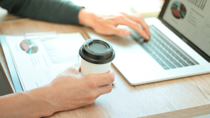 close up. young man analyzes financial data and is drinking take-away coffee .