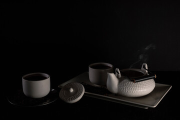 Tea set on dark background illuminated with dim light
