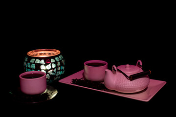 Tea set on dark background illuminated with dim light whit a candle