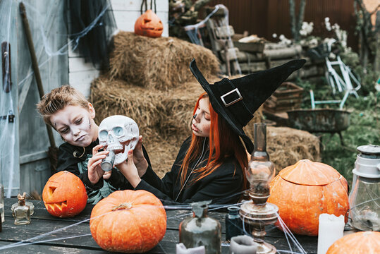 children a boy in a skeleton costume and a girl in a witch costume having fun at a Halloween party on the decorated porch