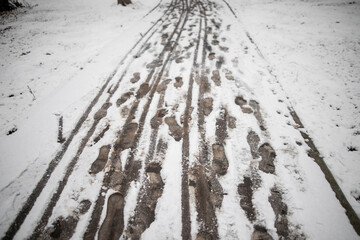 Dirty tracks of snow on asphalt, the first snow, city. Bad ecology, dirty snow. Footprint of shoes on concrete tiles city of November. There are many footprints on road.
