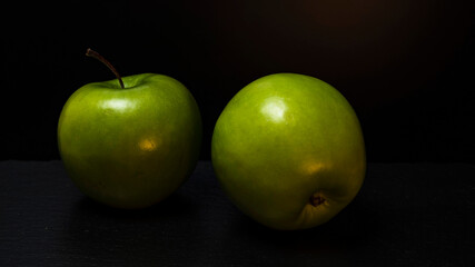 Two ripe fresh green apples isolated on black background. Free copy space. School snacks or organic food concept
