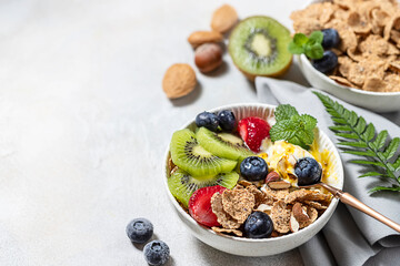 Breakfast with fresh Greek yogurt, strawberries, kiwi and granola on a light concrete background. Healthy food nutrition, snack or breakfast.