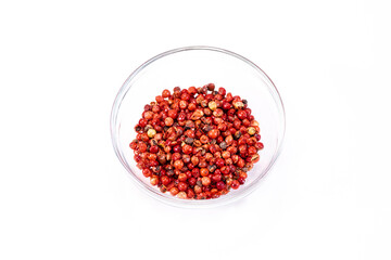 Red pepper corns grains in glass bowl isolated on white background, organic hot species, dried red peppercorns, natural spice. Food concept, chili pepper cosmetic ingredients, culinary. Text space
