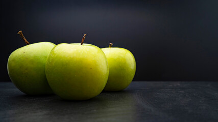 Three ripe fresh green apples isolated on black background. Free copy space. School snacks or organic food concept
