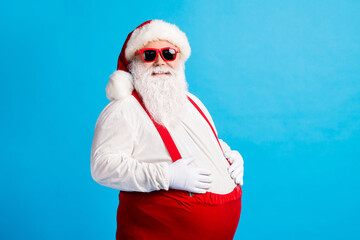 Fototapeta na wymiar Photo of crazy overweight santa claus touch his big belly enjoy x-mas christmas newyear tradition feast wear cap suspenders overalls isolated over blue color background