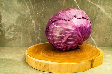 Close up view of fresh red cabbage with water drops on a wooden board on light background. Copy...