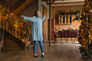 Happy young Caucasian woman dance in beautiful decorated living room enjoy Christmas at home....