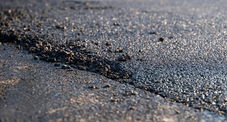 Freshly laid black bitumen asphalt with a high edge to the gravel showing the structure. Laying a...