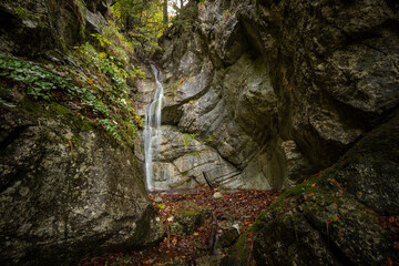 Colorful image of waterfall in the middle of rock formations. Autumn waterscape. Water streaming between rocks. Slovakia