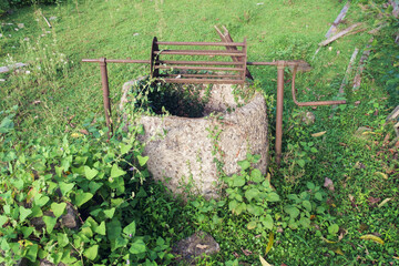  An old abandoned well in a field overgrown with green ivy