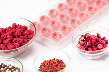 Heart shape confectionery mold with organic melted ruby chocolate and natural dried red berries species filling, hand-crafted premium homemade candies. Chocolate production, candymaking concept
