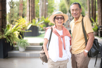 Obraz premium Asian old couple traveler enjoy happy time together while sightseeing in flower garden or public park in summer time. Healthy and positive retirement people lifestyle