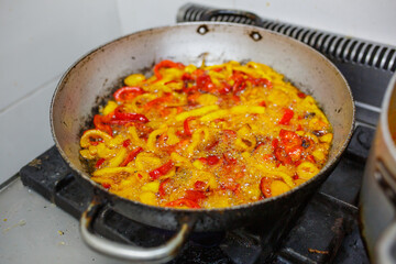 Peperoni rossi e gialli in cottura in olio bollente 