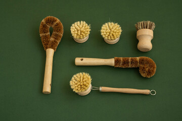 Set of brushes for eco-cleaning the home, washing dishes and surfaces without chemicals on a green surface. Zero waste kitchen cleaning concept. Eco friendly natural cleaning bamboo dish brushes.