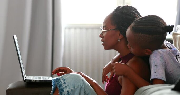 Black woman using laptop with child son