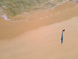 Aerial view of person standing on beach as water runs into the shore
