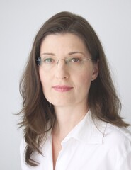 Obraz premium Application photo of a middle aged woman with long dark hair and glasses, neutral light background.