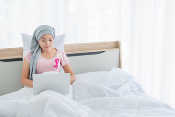 women wearing pink ribbons with smartphone on bed