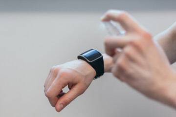 Fototapeta premium casual man spraying alcohol antiseptic on his smart watch.