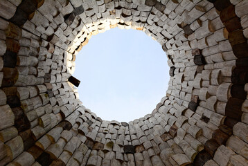 View of the sky in the form of a circle from the bottom up inside a round tower of light wooden bars.