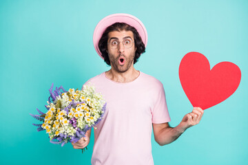 Portrait of surprised hipster guy hold flowers paper heart wear pink cap t-shirt spectacles...
