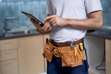 Young builder working on tablet on kitchen background