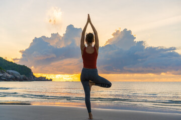 Woman practicing yoga on the beach