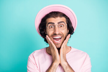 Photo portrait of amazed cheerful man wearing glasses pink casual clothes touching cheeks isolated on vibrant teal color background