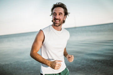 Running man jogging on beach. Male runner training outside working out.