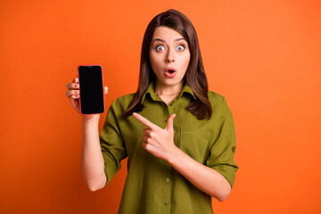 Photo portrait of shocked brunette pointing at copyspace screen smartphone staring isolated on...