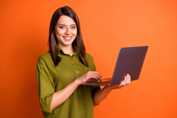 Photo portrait of young female freelancer using laptop fingers on touchpad smiling isolated on bright orange color background