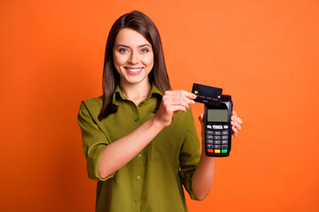 Photo portrait of young girl making purchase with bank card terminal isolated on vivid orange color background