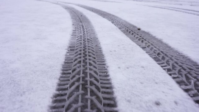 Snow covered road with tire tracks. The camera moves on the trail