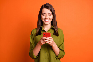 Photo of cheerful lovely lady hold telephone look screen wear green shirt isolated orange color...