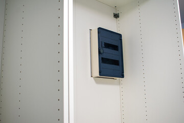 Plastic box with switchboard with home internet router in the wood white wardrobe.