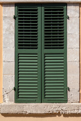 Closed green window on beige wall