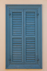 Closed blue window on beige wall