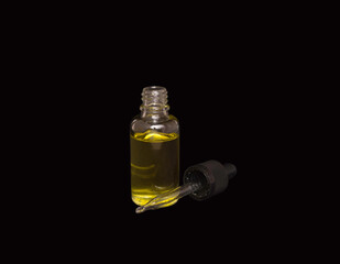 Pipette with cosmetic oil on a black background. A bottle of cosmetics. Skin, hair, and body care. Spa.
