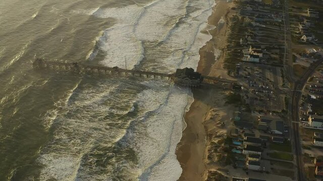 Stunning shot of a pier with waves steadily coming into shore.