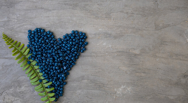 Wax film for depilation with azulene granules in the shape of a heart on a gray background.