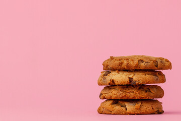 Stacked chocolate chip cookies against pink background