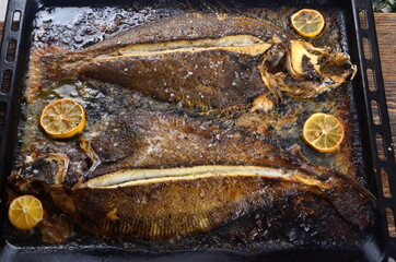 Two whole fresh flounder, butter, and lemon on black baking sheet  Sole Meuniere recipe