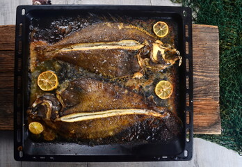 Two whole fresh flounder, butter, and lemon on black baking sheet  Sole Meuniere recipe