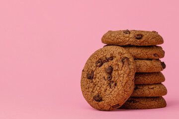 Stacked chocolate chip cookies against pink background